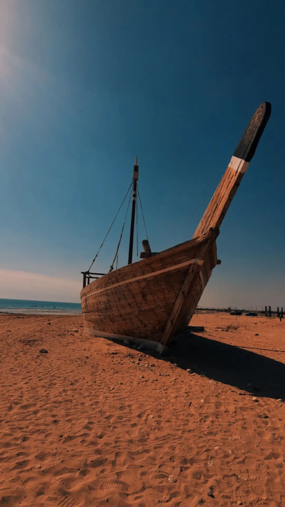 کشتی چوبی پارک شده در ساحل شنی بندر کنگان